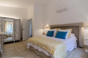 Um quarto com cama, abajures, guarda-roupa e espelho.