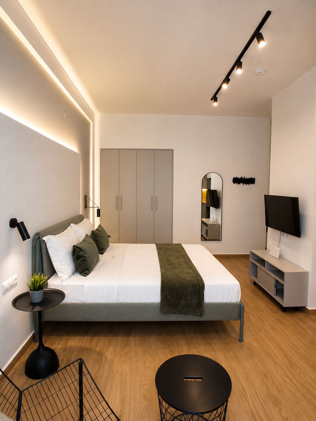 Une chambre moderne avec un lit, des tables de chevet, un téléviseur et une armoire.