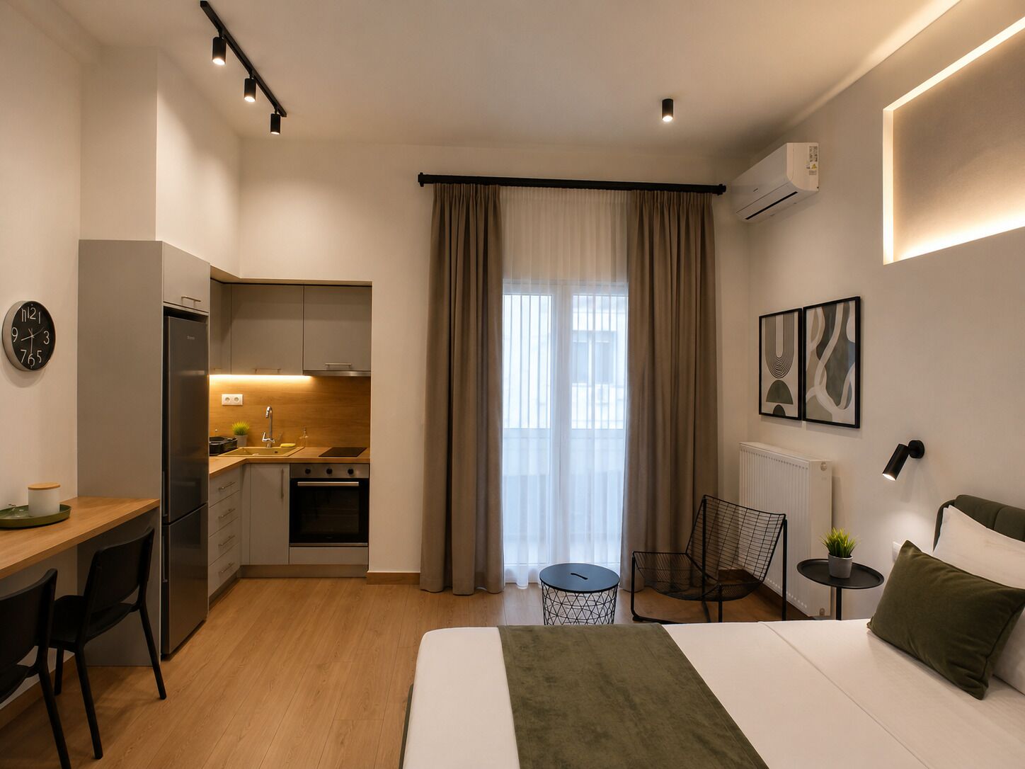 Ein modernes Schlafzimmer mit Bett, Schreibtisch und einer Küchenzeile.