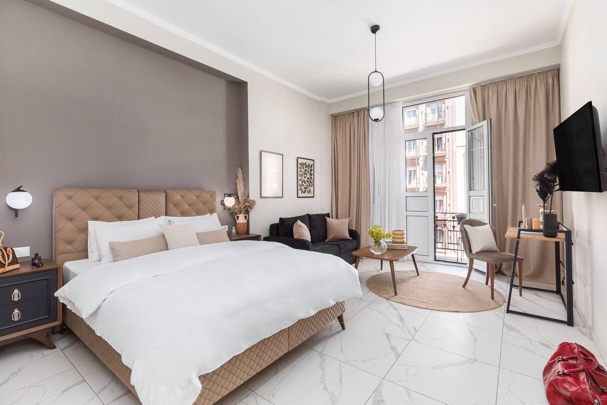 Ein modernes Hotelzimmer mit einem großen Bett, einer Couch, einem kleinen Tisch und einem Fernseher.
