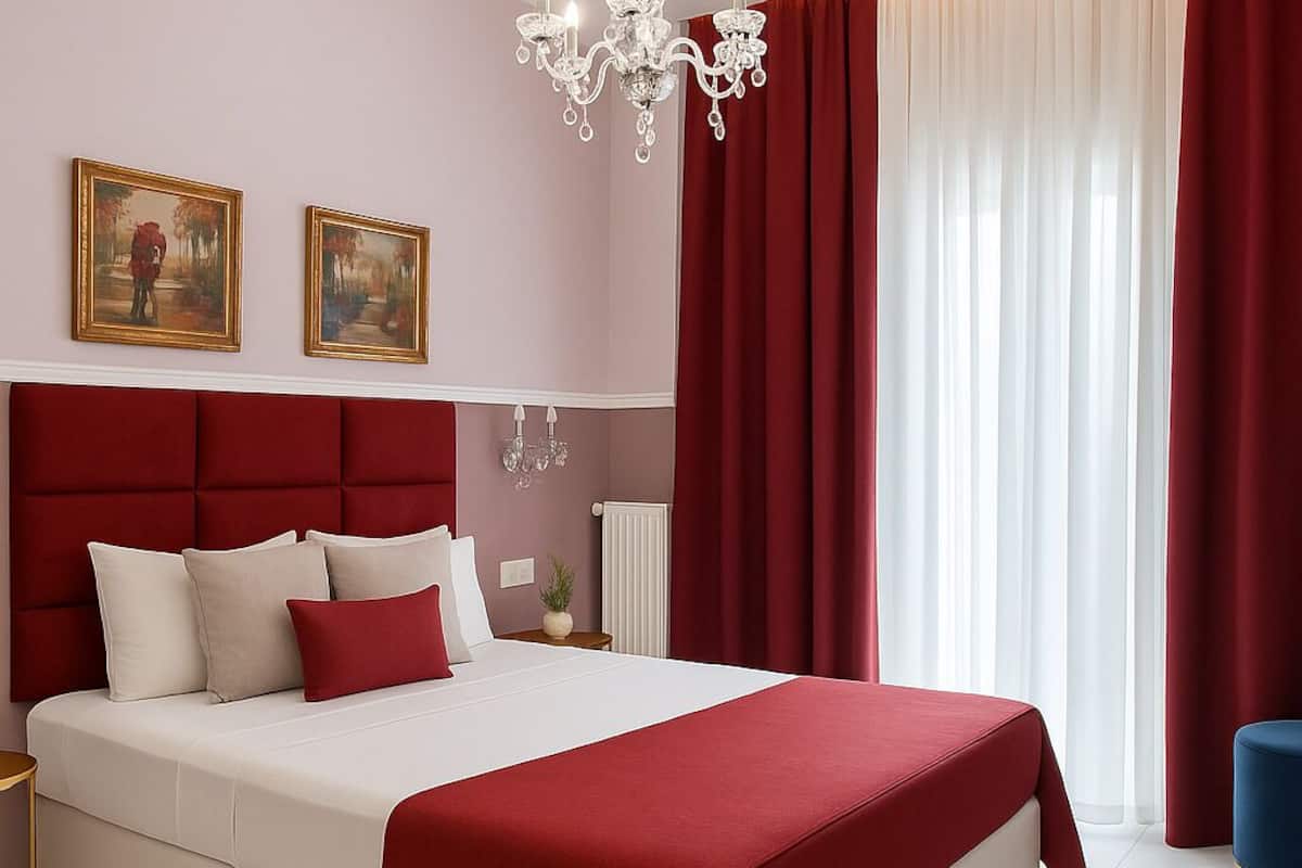 Ein modernes Schlafzimmer mit einem großen Bett, roten Vorhängen, einer Chandelieber und zwei Bildern an der Wand.