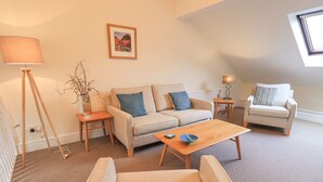 A modern living room with a sofa, a coffee table, a side table, a lamp, and a chair. - Beechside (Ambleside)