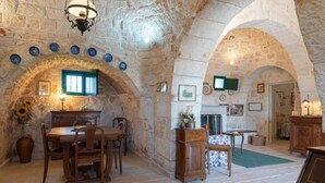 A rustic stone interior with a dining area, wooden furniture, and a fireplace. - Stile e Relax nei Trulli by Wonderful Italy (Martina Franca)