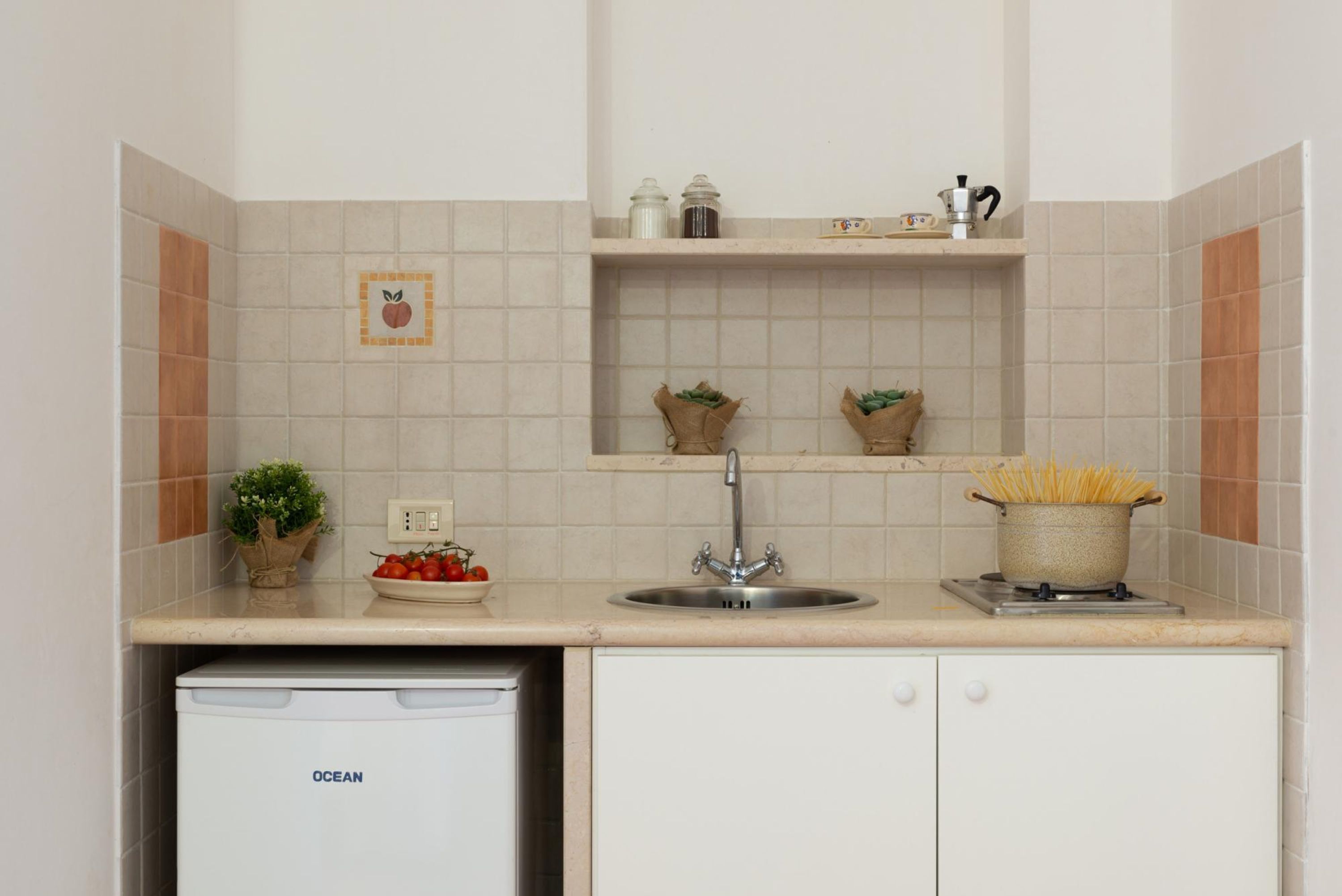 A kitchen with a dishwasher, sink, and various kitchen items on the countertop.
