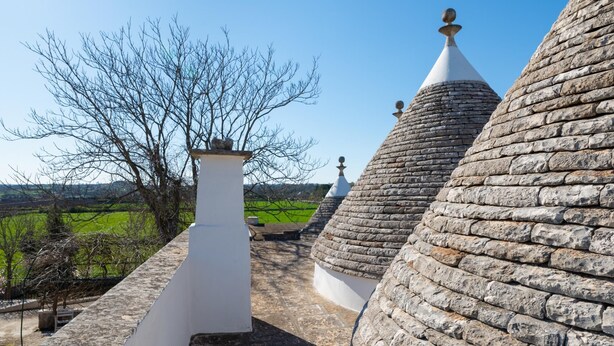 A stone building with multiple conical roofs and a white chimney. - Stile e Relax nei Trulli by Wonderful Italy (Martina Franca)