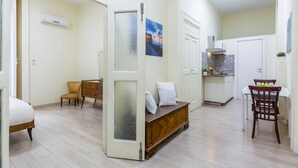 Un espace de vie spacieux comprenant un banc en bois, une petite table et un coin cuisine.