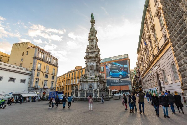 Une place publique avec un monument central, entourée de bâtiments historiques.