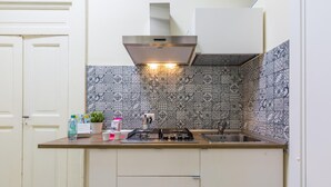 Une cuisine compacte équipée d’une cuisinière à gaz, d’un évier et d’un crédence décorée.