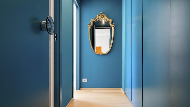Een gang met blauwe wanden en een houten vloer.