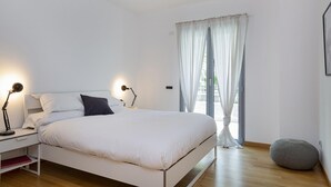 A bedroom with a bed, bedside tables, lamps, a window with curtains, and a round ottoman. - Viviboccadasse by Wonderful Italy - Tulipano (Genoa)