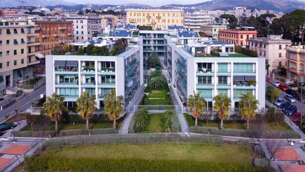 A modern building with multiple floors, large windows, and a central courtyard with palm trees. - Viviboccadasse by Wonderful Italy - Tulipano (Genoa)