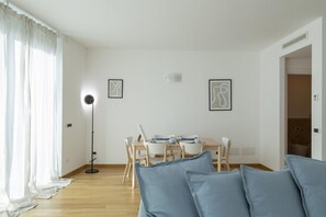 Un salon moderne avec un coin repas, comprenant un canapé, une table à manger avec des chaises et un lampadaire.