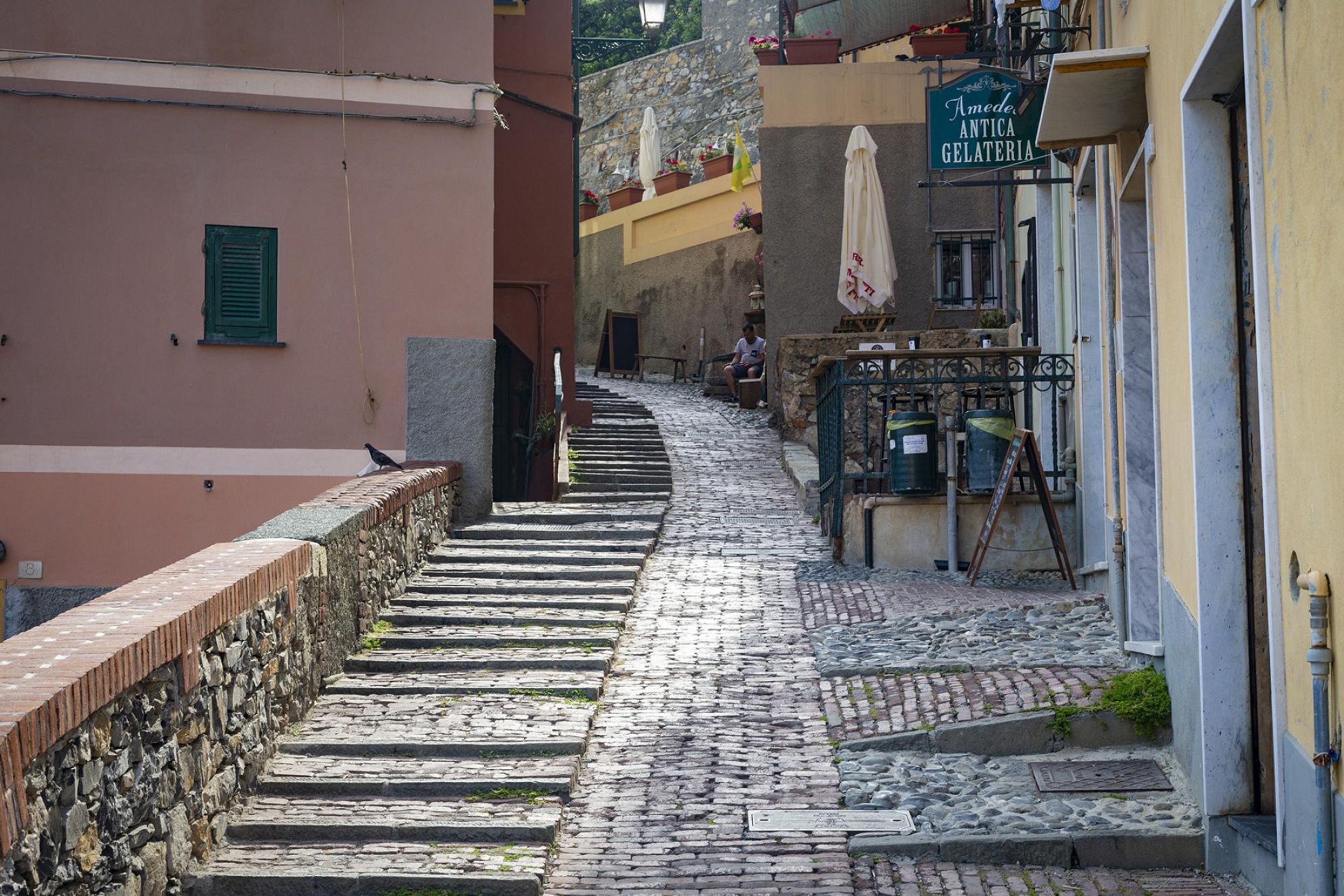 A cobblestone street leading to a building with a sign reading "Amedeo Antica Gelateria".