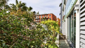 A narrow pathway flanked by dense foliage and a modern building with large windows and balconies. - Viviboccadasse by Wonderful Italy - Tulipano (Genoa)