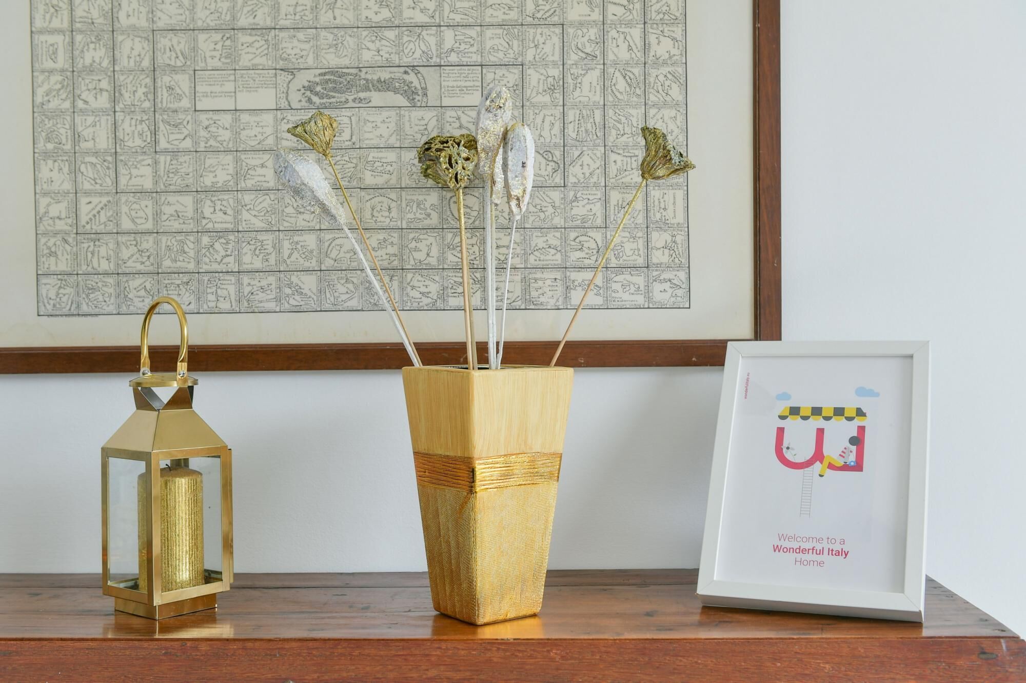 A wooden vase with decorative elements, a golden lantern, and a framed welcome sign.
