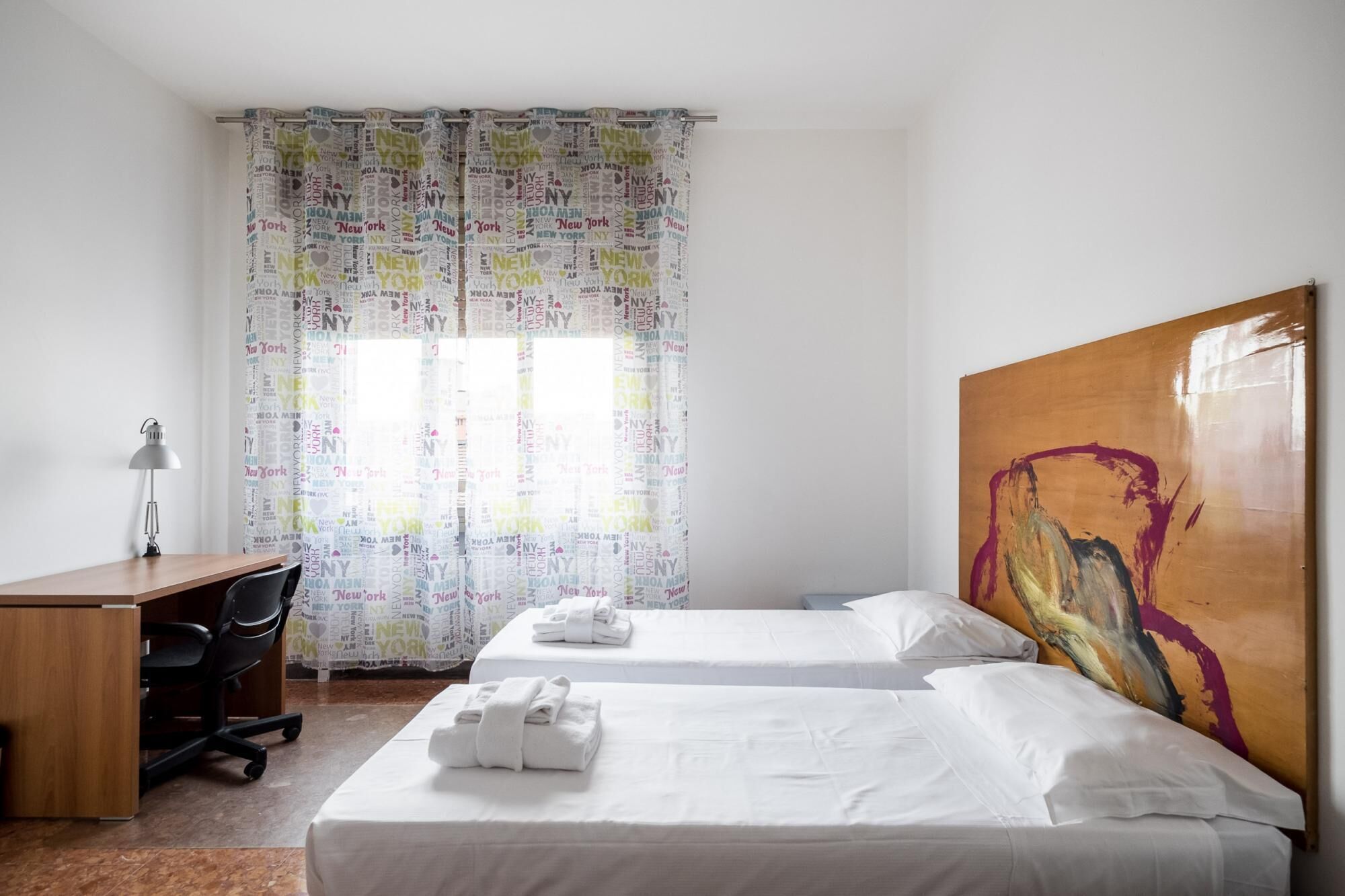 A hotel room with two beds, a desk, and a chair.