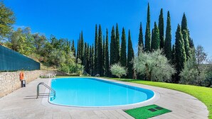 A swimming pool with a stone deck, surrounded by trees and a stone wall. - Al Vittoriale 3 by Wonderful Italy (Gardone Riviera)