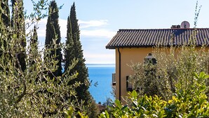 A coastal building with a tiled roof, surrounded by olive trees and cypress trees. - Al Vittoriale 3 by Wonderful Italy (Gardone Riviera)