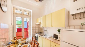Une cuisine de taille réduite avec des meubles de couleur jaune, une cuisinière, un four à micro-ondes et un réfrigérateur.