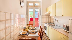 Une cuisine avec une table à manger dressée pour le repas, une horloge au mur et des placards.