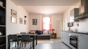 A modern kitchen with a built-in oven and microwave, a dining area with a table and chairs, and a living area with a sofa and a coffee table.