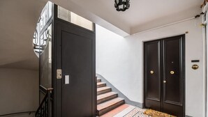A staircase leading to a dark wooden door with a doormat that reads "home is where the heart is."