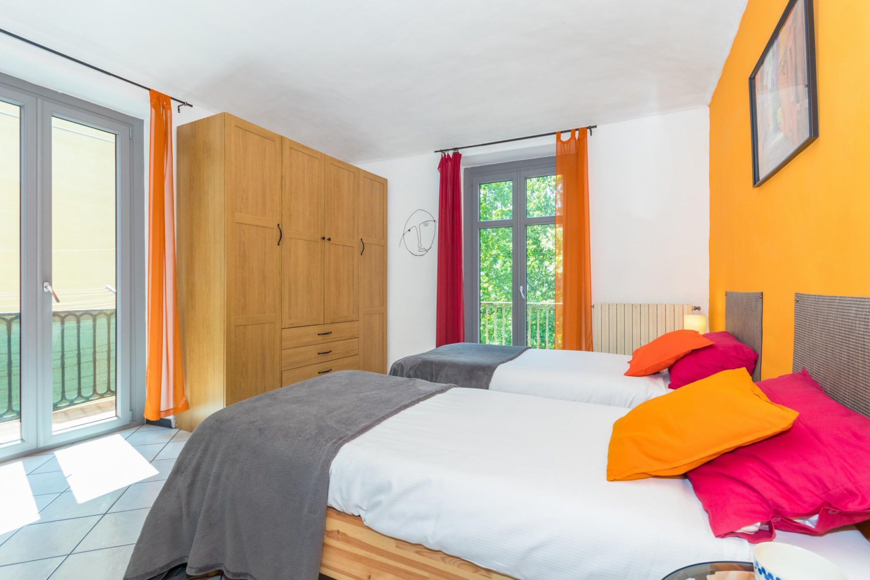Une chambre avec deux lits, une armoire en bois et une fenêtre avec des rideaux.