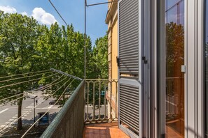 A balcony with a view of a tree-lined street and a closed shop door.