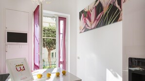 A kitchen with a countertop, a framed welcome sign, a window with pink curtains, and a painting on the wall. - Vernazzola Family Apartment by Wonderful Italy (Genoa)