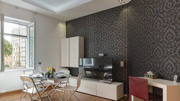 A modern living room with a dining area, a large window, and a patterned wallpaper. - Vernazzola Family Apartment by Wonderful Italy (Genoa)
