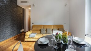 A modern living room with a sofa, a dining table set with plates and glasses, and a patterned wall. - Vernazzola Family Apartment by Wonderful Italy (Genoa)