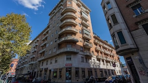 A multi-story building with balconies, a street in front, and various shops. - Torino 3 0 Sulla Via del Treno by Wonderful Italy (Turin)