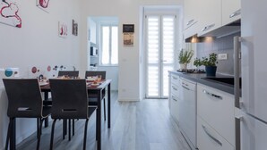 A modern kitchen with white cabinets, a dining area with black chairs, and a view of the outside through a door. - Torino 3 0 Sulla Via del Treno by Wonderful Italy (Turin)