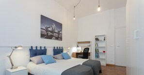 Une chambre moderne avec un grand lit, des tables de chevet, un bureau et une bibliothèque.