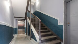 Una escalera con barandilla de metal, escalones alfombrados y un felpudo rojo.