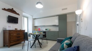 Una sala de estar moderna con un sofá gris, un aparador de madera y una mesa de comedor con sillas.