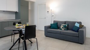 Un espacio habitable compacto con kitchenette, comedor y sofá con cojines.