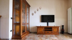 Un salon avec un meuble en bois, un téléviseur à écran plat fixé au mur et un radiateur.