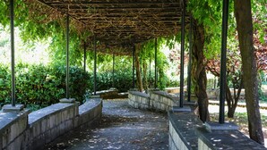 Une allée couverte, dotée de rampes en pierre et d’un auvent soutenu par des poteaux métalliques.