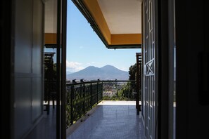 En balkon med gelænder, flisegulv og udsigt til et bjerg.