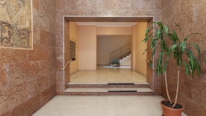 A marble-floored hallway with a potted plant, a staircase, and a door leading to another room. - Carignano Design Apartment 9 by Wonderful Italy (Genoa)
