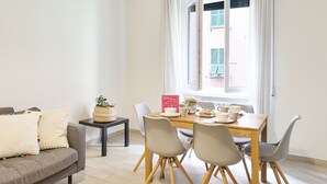 A dining area with a table, chairs, a small side table, and a sofa. - Carignano Design Apartment 9 by Wonderful Italy (Genoa)