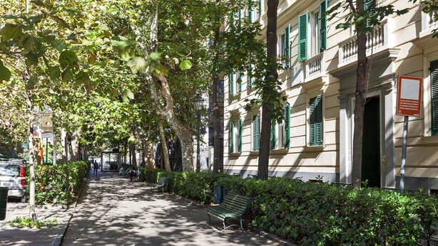 A tree-lined sidewalk with benches and a building with green shutters. - Carignano Design Apartment 9 by Wonderful Italy (Genoa)
