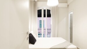 A bedroom with a bed, a window with curtains, a balcony with chairs, and an air conditioning unit. - Carignano Design Apartment 9 by Wonderful Italy (Genoa)