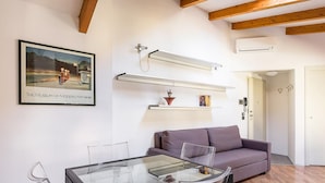 A modern living room with a glass table, a purple sofa, and a mounted artwork of a motorcycle. - Chez Cristina by Wonderful Italy (Bologna)