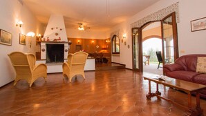 A spacious living room with a fireplace, wicker chairs, a red sofa, and a ceiling fan. - Daller Bianca - BK in Soiano del Lago (Soiano del Lago)
