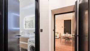 Um apartamento moderno com área de lavanderia, espaço para refeições e cozinha.