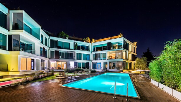 Un hôtel moderne doté d’une piscine, de nombreux balcons et d’un espace extérieur bien éclairé.
