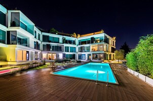 Un hotel moderno con piscina, diversi balconi e una zona esterna ben illuminata.