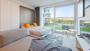 Une chambre d’hôtel moderne dotée d’un grand lit, d’un canapé, d’un bureau et d’un balcon avec vue sur la piscine.